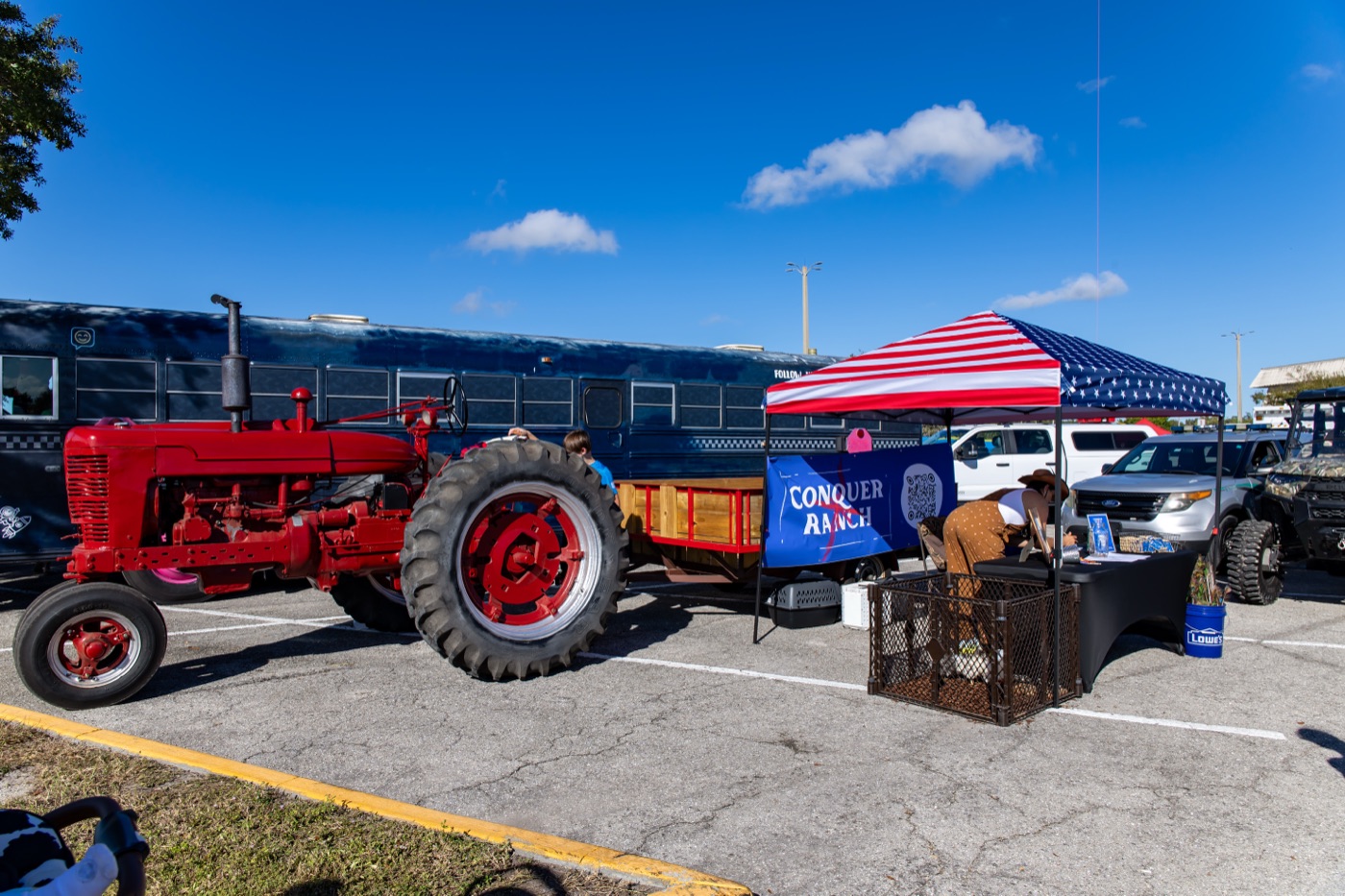 Conquer Ranch’s outdoor event booth with a red tractor, animal pen, and patriotic canopy