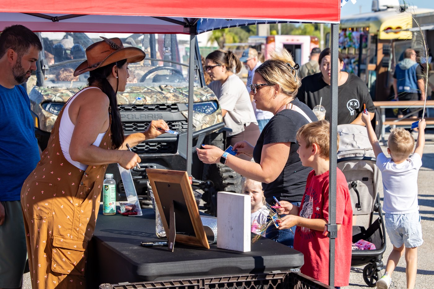 A Conquer Ranch representative talks with an adult and child across the outreach table.