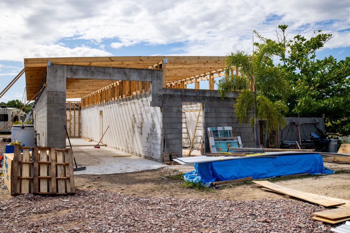 An open ranch building with new timber roof framing and a blue water trough