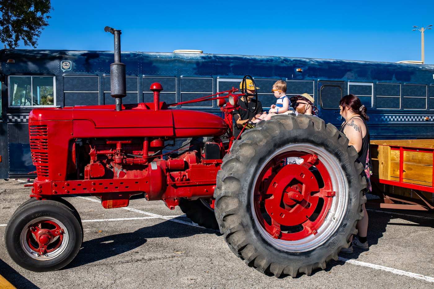 A vintage red tractor beside the Conquer Ranch activity area at Touch A Truck.