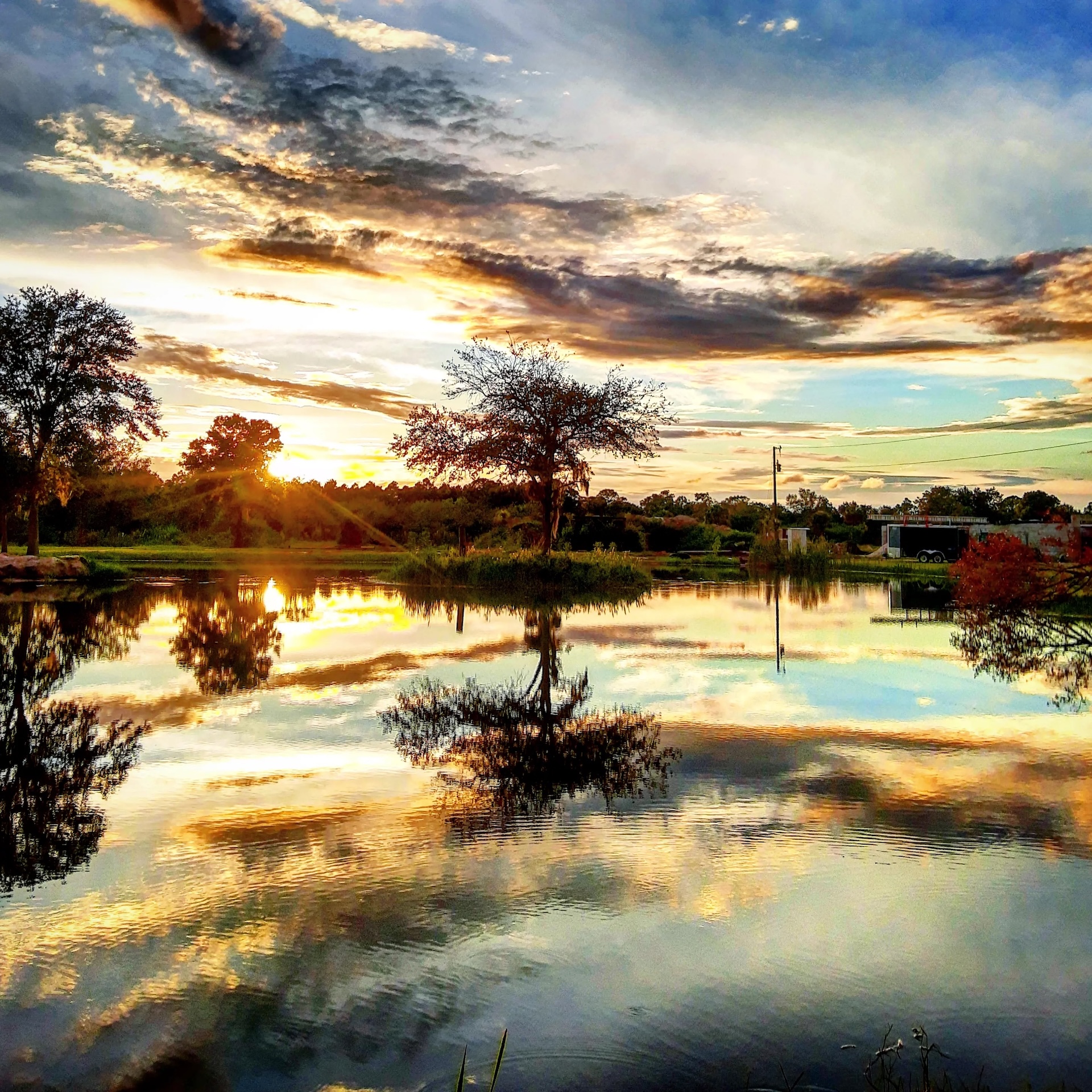 A bright sunset reflected in the ranch pond